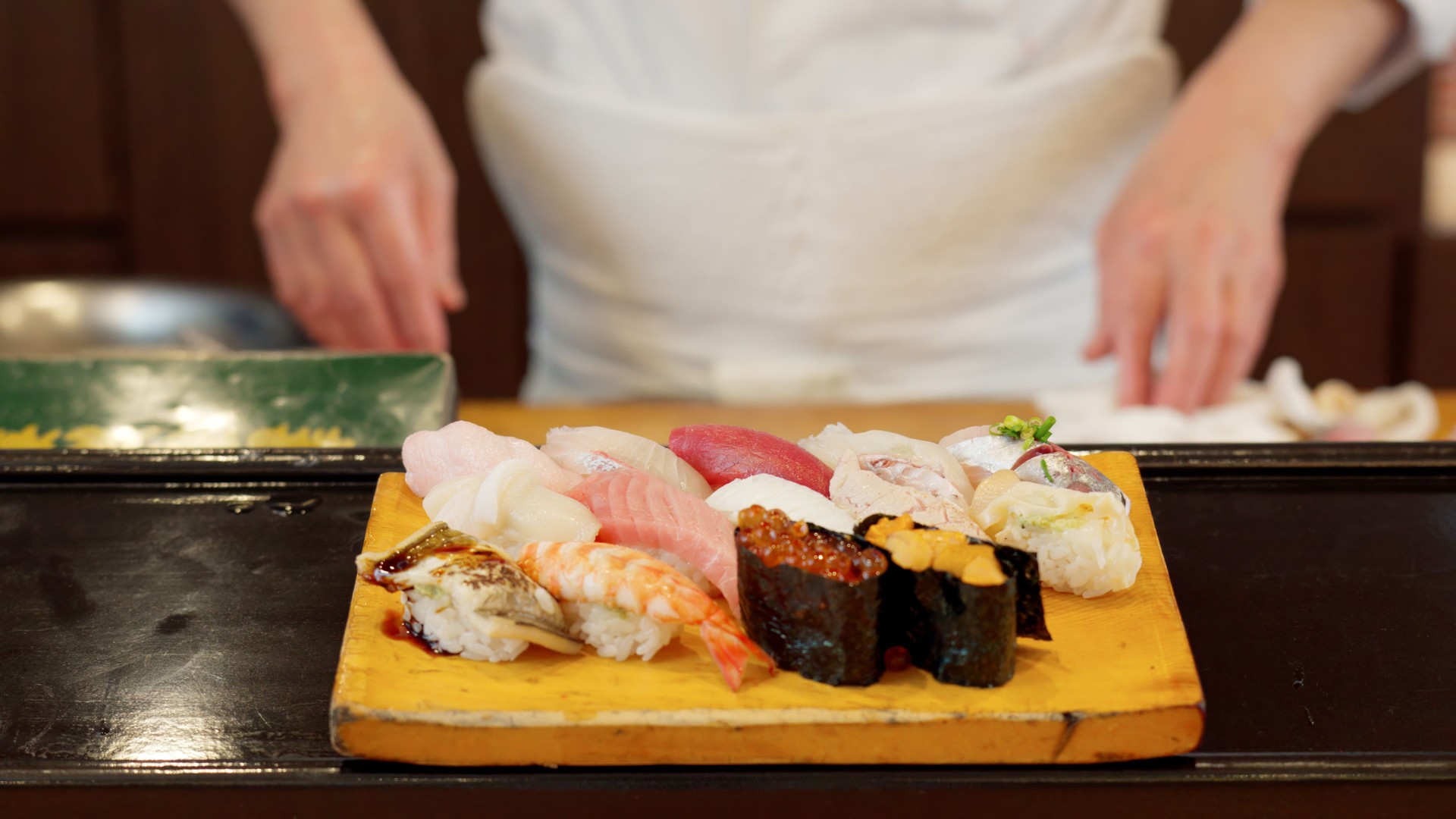 Chef's hands offering nigiri sushi